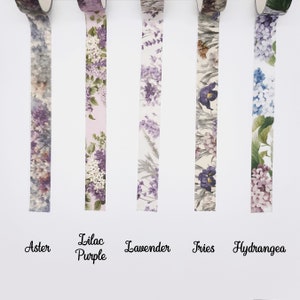 May include: Five rolls of decorative washi tape featuring floral patterns labelled Aster, Lilac Purple, Lavender, Iris, and Hydrangea. Each strip displays distinct botanical illustrations in shades of purple, blue, green, and white on a white background.