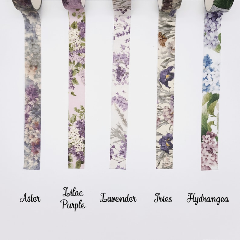 May include: Five rolls of decorative washi tape featuring floral patterns labelled Aster, Lilac Purple, Lavender, Iris, and Hydrangea. Each strip displays distinct botanical illustrations in shades of purple, blue, green, and white on a white background.