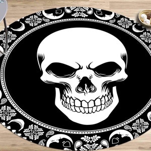May include: Black and white round rug with a skull design in the center. The skull is surrounded by a paisley pattern.