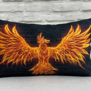 Könnte beinhalten: Ein schwarzes und orangefarbenes Kissen mit einem feurigen Phönix-Design.