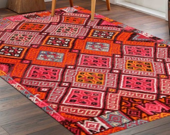 May include: A colorful rug with a geometric pattern in shades of pink, orange, and black. The rug has a diamond-shaped design with intricate details.