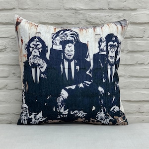 Puede incluir: Una almohada decorativa con fondo blanco y una imagen en blanco y negro de tres chimpancés con traje y corbata. Los chimpancés miran a la cámara y tienen las manos sobre los ojos.