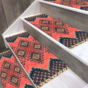 May include: Stair treads with a vibrant coral background and intricate navy blue and gold geometric patterns. The stair treads are installed on wooden stairs with white trim, adding a decorative and safe element to the home.