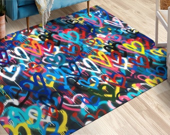 Puede incluir: Una alfombra colorida con un diseño de estilo graffiti que presenta un patrón repetitivo de corazones en varios colores, incluyendo rosa, azul, amarillo, rojo y blanco. Los corazones están pintados sobre un fondo negro.