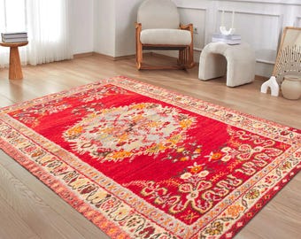 May include: A vibrant red area rug with an intricate floral pattern in shades of yellow, orange, and cream. The rug has a central medallion design and a detailed border. The rug is rectangular and placed on a wooden floor.