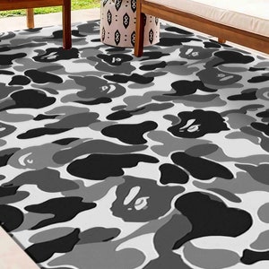May include: A black and white camouflage patterned rug with a white background. The rug has a repeating pattern of black and gray shapes.