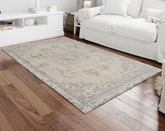 May include: A light beige area rug with a floral pattern in shades of blue, pink, and cream. The rug has a distressed, vintage look and is perfect for adding a touch of bohemian style to any room.