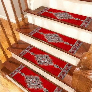 May include: Red stair treads with an ornate, patterned design. The treads feature a central medallion and border details in shades of blue, cream, and black. The stair treads are rectangular and placed on wooden stairs.