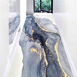 May include: A long, narrow hallway runner rug with an abstract design featuring swirling grey and blue marble patterns with gold accents.