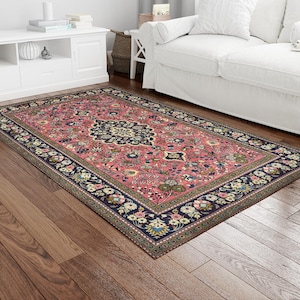 May include: A pink and blue patterned rug with a floral design. The rug has a dark blue border with intricate details.