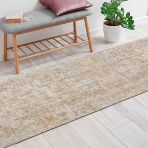 Könnte beinhalten: Ein beige-grauer Läufer mit Muster und einem dezenten Used-Look. Der Läufer liegt auf einem hellen Holzboden in einem Flur mit einer Holzbank und einer Topfpflanze.