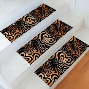 May include: Three non-slip stair treads with a black and gold abstract pattern. The treads are made of a soft, durable material and are designed to help prevent slips and falls on stairs.