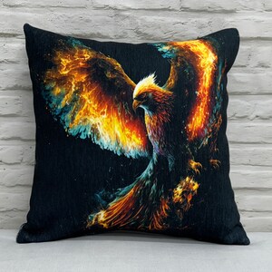 May include: A black throw pillow with a colorful image of a phoenix rising from flames. The phoenix is depicted in shades of orange, yellow, and blue.
