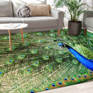 Könnte beinhalten: Ein grüner und blauer Pfauenfederteppich mit einer detaillierten Illustration der Schwanzfedern eines Pfaus. Der Teppich liegt auf einem Holzboden in einem Wohnzimmer.