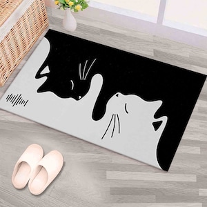 Puede incluir: Una alfombra de entrada negra y blanca con un diseño de dos gatos que se miran. Los gatos están en un diseño yin yang, con un gato negro y el otro blanco.