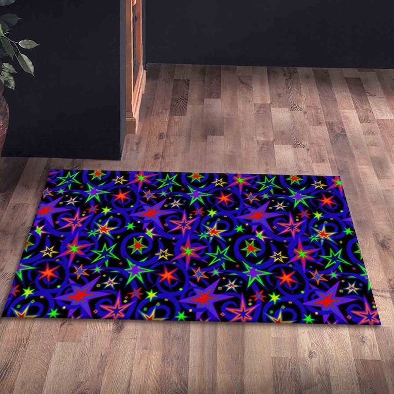 Pu&ograve; includere: Un tappeto blu con un motivo ripetitivo di stelle e vortici colorati. Le stelle sono in tonalit&agrave; di rosso, giallo, verde e viola.