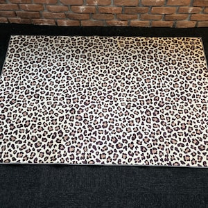 May include: A white and brown leopard print rug with a gray border.