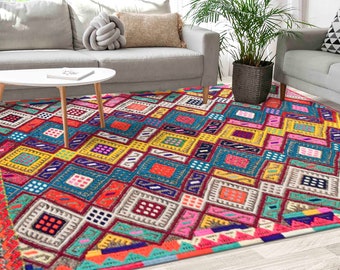 May include: A vibrant, geometric area rug with a colorful patchwork design. The rug features a mix of squares and rectangles in shades of red, blue, yellow, and pink. The rug is placed in a living room setting with a sofa and coffee table.