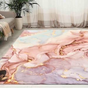 Può includere: Un tappeto da area astratto rosa, bianco e oro con un design marmoreo. Il tappeto ha una texture morbida e soffice ed è perfetto per aggiungere un tocco di eleganza a qualsiasi stanza.