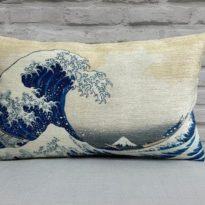 May include: A decorative pillow with a beige background featuring a blue and white print of the Great Wave off Kanagawa by Katsushika Hokusai.