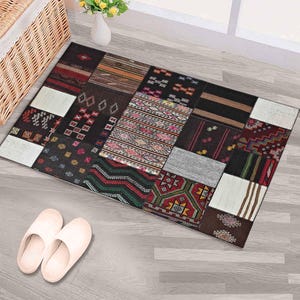 May include: A rectangular patchwork rug with various geometric and patterned designs in shades of brown, red, black, and white. The rug is placed on a light gray wooden floor, with a pair of white slippers nearby.