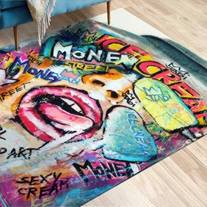 May include: A colorful rug with a graffiti-style design featuring a woman's face, lips, and tongue. The design includes the words "Ice Cream", "Money", "Street", "Girl", "Pop Art", and "Sexy Cream".