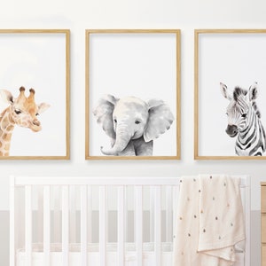 May include: Three framed watercolor paintings of animals. The first painting features a giraffe with a light brown and orange coat. The second painting features a gray elephant with a trunk. The third painting features a zebra with black and white stripes.