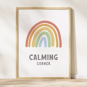 May include: A framed print with a rainbow design in shades of orange, yellow, green, and blue. The text "CALMING CORNER" is printed below the rainbow.