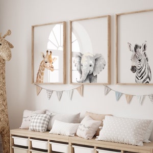 May include: Three framed animal prints in a nursery setting. The prints feature a giraffe, an elephant, and a zebra. The prints are in a watercolor style and have a white background.