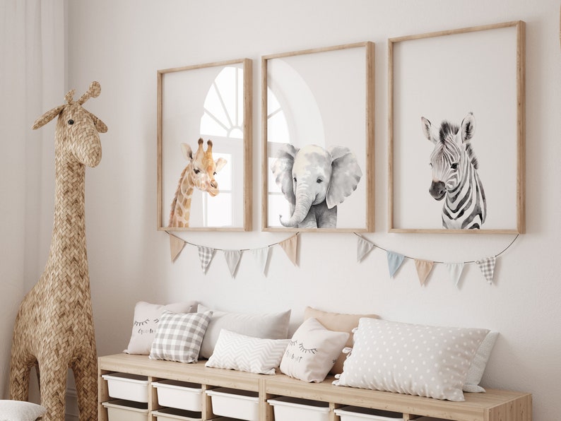 May include: Three framed animal prints in a nursery setting. The prints feature a giraffe, an elephant, and a zebra. The prints are in a watercolor style and have a white background.