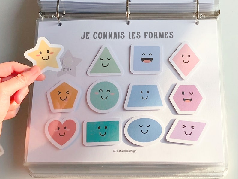 Op de afbeelding: Een wit vel papier met de tekst "JE CONNAIS LES FORMES" bovenaan. Er zijn 12 gekleurde vormen met vrolijke gezichten erop. De vormen omvatten een ster, een driehoek, een vierkant, een ruit, een vijfhoek, een cirkel, een trapezium, een zeshoek, een hart, een rechthoek, een ovaal en een parallellogram.