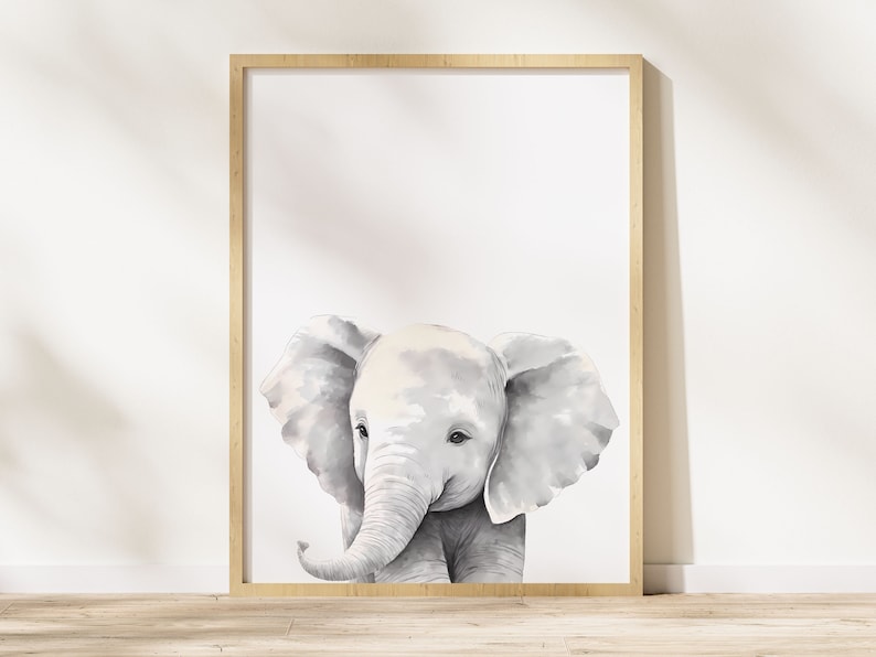 May include: A watercolor painting of a gray baby elephant with large ears. The elephant is looking to the left of the image. The painting is framed in a light wood frame.
