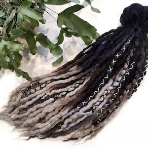 May include: A set of black, brown and grey wool dreadlocks with white stitching. The dreadlocks are tied together at the top.
