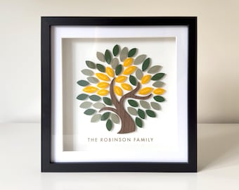 May include: Framed family tree art with a black frame, white mat, and a tree design. The tree has a brown trunk and branches, with green, gray, and yellow leaves. The text "THE ROBINSON FAMILY" is printed below the tree.