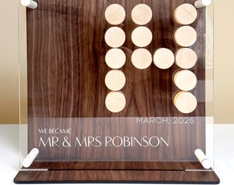 May include: A wooden wedding sign with the text "WE BECAME MR & MRS ROBINSON MARCH, 2026". The sign features a dark wood grain background with a clear acrylic overlay. The date is represented by wooden circles.