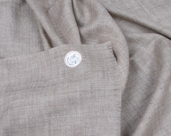 May include: A light brown pashmina shawl with a fringed edge. The shawl is made of soft, luxurious fabric and has a subtle sheen. A small white tag with the text "100% Cashmere" is attached to the shawl.
