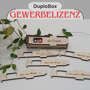 Pode incluir: Uma caixa de madeira com as palavras "DuploBox GEWERBELIZENZ" no topo. A caixa está aberta e tem várias peças de madeira no interior com diferentes mensagens gravadas nelas, como "bist Perfekt", "bist die Liebe meines Lebens", "bist der Beste", "bist die Beste" e "bist einfach Wunder".