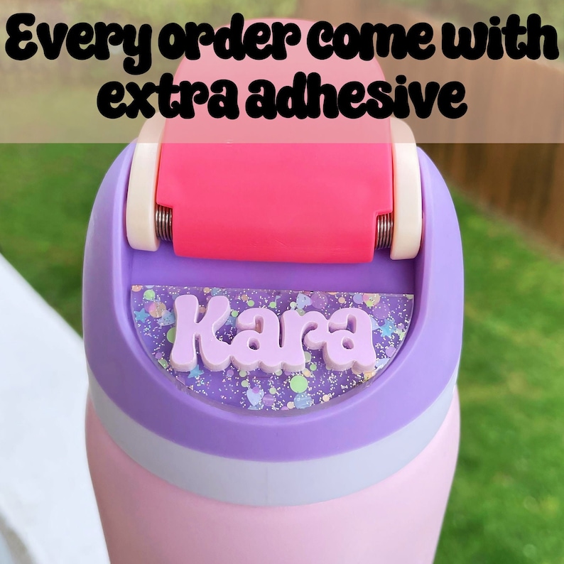 May include: A pink and purple water bottle with a clear lid and a roller to apply adhesive. The lid has a purple and glitter sticker with the name "Kara" on it.