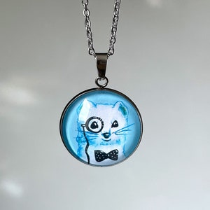 stainless steel cabochon necklace with watercolor art of a white ermine, member of the family of the ferrets, in white and blue