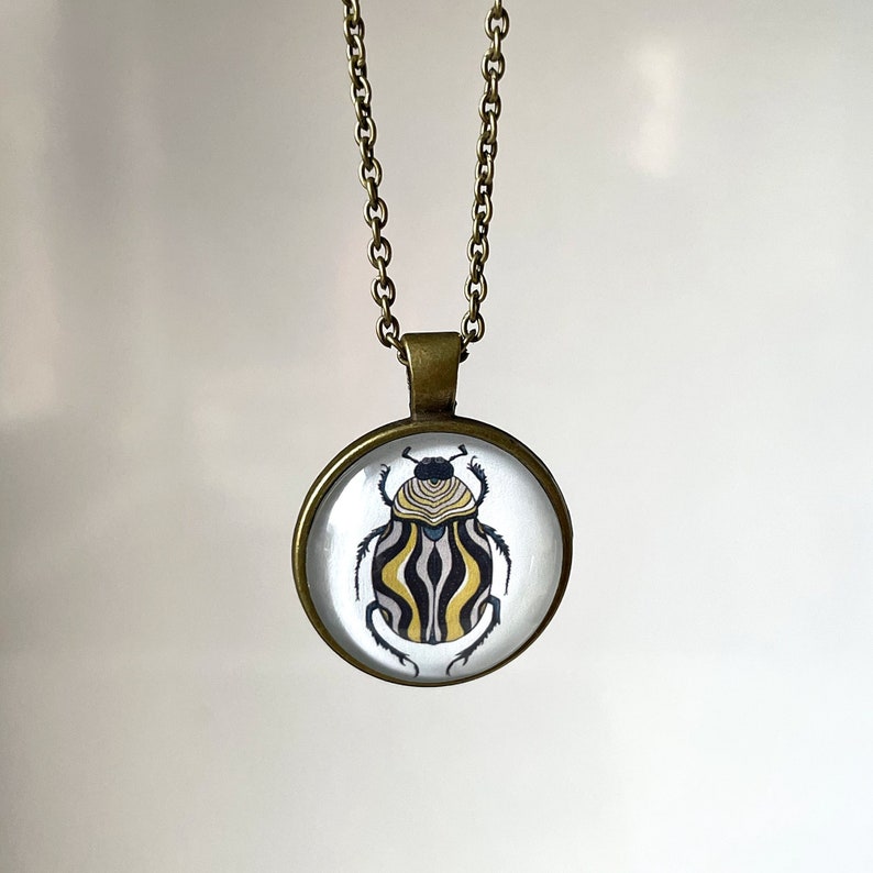 Antique bronze color round pendant necklace with a striped beetle art