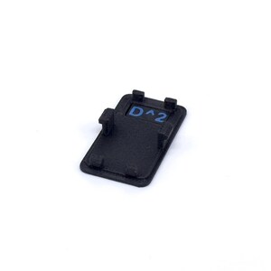 May include: Black plastic button with a blue inscription that reads "D^2".