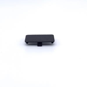 May include: A black plastic cover for a small electronic device. The cover has a textured surface and a small tab on the side.