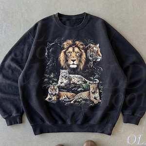 May include: A black crewneck sweatshirt featuring a central graphic print of various big cats, including a lion, tiger, leopard, and panther, surrounded by foliage. The text OLD SCHOOL CULT is visible in the bottom right corner of the image.