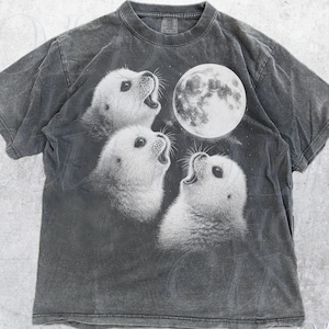 May include: A grey t-shirt with a graphic of three white seals gazing at a full moon. The shirt has a vintage, faded look. The text "OLD SCHOOL CULT" is visible on the bottom right.