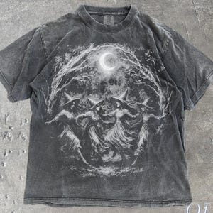 May include: A grey t-shirt featuring a graphic of three figures dancing beneath a crescent moon, framed by a forest arch. The text "OLD SCHOOL CULT" is at the bottom right. The word "Pepper" is at the bottom left.