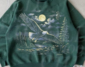 May include: Forest green sweatshirt featuring a detailed graphic of a bald eagle in flight against a moonlit forest backdrop. The design includes a full moon, trees, and a second eagle. The text "OLD SCHOOL CULT" is visible.
