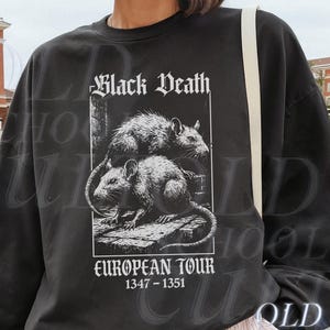 May include: Black sweatshirt featuring a graphic of two rats and the text "Black Death EUROPEAN TOUR 1347-1351". The model is 5'8" and wearing XL. The sweatshirt is black.