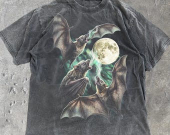 May include: Dark gray t-shirt featuring a graphic of three bats with outstretched wings, howling at a full moon. The design includes green and white accents. The text "OLD SCHOOL CULT" is printed on the bottom right.