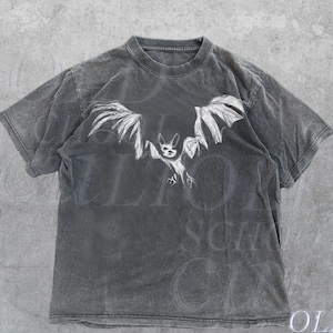 May include: A black t-shirt featuring a white graphic of a bat with its wings outstretched. The text "OLD SCHOOL CULT" is printed in white at the bottom of the shirt.