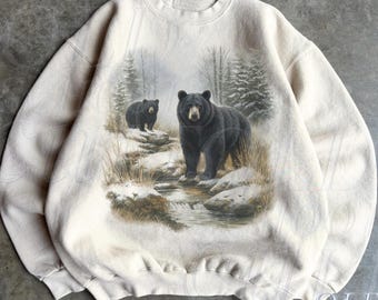 May include: Sand-colored sweatshirt featuring a detailed graphic of two black bears in a snowy forest scene. The bears stand near a stream, with trees in the background. The text "OLD SCHOOL CULT" is printed on the lower right.